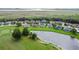 Aerial view showcases homes nestled around a pond and golf course, surrounded by lush greenery at 1976 The Oaks Blvd, Kissimmee, FL 34746