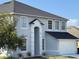Two-story home featuring light gray stucco, white trim, and a black roof under a clear blue sky at 1976 The Oaks Blvd, Kissimmee, FL 34746