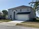 Two-story home featuring a driveway, manicured lawn, and attached two-car garage at 1976 The Oaks Blvd, Kissimmee, FL 34746
