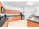 Well-lit kitchen features ample oak cabinetry, black countertops, stainless steel appliances, and tile flooring, offering functionality and style at 253 Aldridge Ln, Davenport, FL 33897