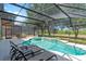 Screened-in pool area featuring a spa, outdoor seating, and scenic views of the surrounding greenery at 253 Aldridge Ln, Davenport, FL 33897