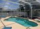 Screened-in pool and spa area, featuring a lush backyard and lounge chairs for relaxation at 314 Saddle Ridge Dr, Davenport, FL 33896