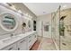 Bright bathroom features double sinks with white cabinets and a marble tiled walk-in shower at 4337 Summer Breeze Way, Kissimmee, FL 34744