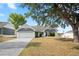 Home featuring an attached two car garage, mature trees and a front yard swing set at 5512 Hamlin Close, Davenport, FL 33896