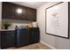 This laundry room has dark cabinets, a washer and dryer set, and a laundry symbol art piece at 6413 Clover St, Lake Hamilton, FL 33851