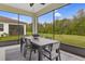This screened-in patio offers an outdoor dining space with views of the lawn and surrounding trees at 6413 Clover St, Lake Hamilton, FL 33851