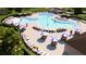 Aerial view of a community pool surrounded by lounge chairs, tables, and umbrellas at 6413 Clover St, Lake Hamilton, FL 33851
