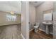 Neutral half bath with pedestal sink and wood look ceramic tile flooring adjacent to adjacent to open living area at 6452 Sprucepine Ln, St Cloud, FL 34771