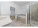 Bright bathroom features double vanity sinks, a bathtub, and a glass door shower at 6452 Sprucepine Ln, St Cloud, FL 34771
