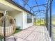 The screened-in lanai features a brick floor, hanging chair, and views of the lush landscaping at 684 San Augusto Dr, Poinciana, FL 34759