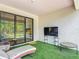 Enjoy a relaxing outdoor space with this covered patio, featuring turf, stylish furniture, and a wall-mounted television at 684 San Augusto Dr, Poinciana, FL 34759