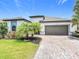 Beautiful home featuring a well-manicured lawn, tropical landscaping, a paver driveway, and a spacious two-car garage at 684 San Augusto Dr, Poinciana, FL 34759