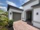 Inviting front entrance with arched portico, gray-toned carriage door, and brick paved driveway at 684 San Augusto Dr, Poinciana, FL 34759