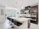 Modern kitchen with bar seating, stainless steel appliances, and dark cabinets open to a dining area at 684 San Augusto Dr, Poinciana, FL 34759