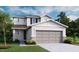 Two story home with a two car garage, neutral color palette, stone accents, and manicured lawn at 737 Lake Dell Rd, Dundee, FL 33838
