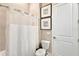 Well-lit bathroom showcases a toilet, shower with white curtain, and framed artwork at 7740 Sandy Ridge Dr # 236, Reunion, FL 34747