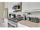 Close-up of modern stainless steel gas range and oven, white cabinets and countertops with small appliances at 7740 Sandy Ridge Dr # 236, Reunion, FL 34747