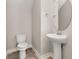 Stylish half-bath with a pedestal sink, decorative mirror, and wood-look tile flooring at 7878 Greengard St, Orlando, FL 32827