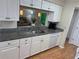 Well-lit kitchen featuring white cabinets, sleek granite countertops, and a convenient serving hatch to the living area at 8 Buck Cir # 8, Haines City, FL 33844