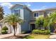 Two-story townhome featuring mature palm trees, neat landscaping, and a well-manicured lawn at 1002 Chalcedony St, Kissimmee, FL 34744