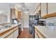 Clean kitchen featuring black appliances, white countertops, and wood-look laminate flooring at 1065 S Hiawassee Rd # 1425, Orlando, FL 32835