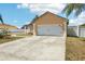 Charming tan home featuring a two-car garage, a well-maintained lawn, and a beautiful blue sky at 115 Anzio Dr, Kissimmee, FL 34758