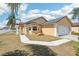 Charming tan home featuring a two-car garage, a well-maintained lawn, and a beautiful blue sky at 115 Anzio Dr, Kissimmee, FL 34758