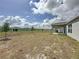 Wide-open backyard with young trees, a covered patio, and a view of neighboring homes at 119 Summerlin Loop, Haines City, FL 33844