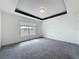 A bright bedroom boasts neutral carpeting and a decorative tray ceiling with a modern ceiling light at 119 Summerlin Loop, Haines City, FL 33844