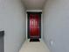 A close view of a red front door with black trim and gray walls at 119 Summerlin Loop, Haines City, FL 33844