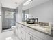 Bathroom featuring double vanity sinks, granite countertops, and tiled shower with glass doors at 13044 Lakeshore Grove Dr, Winter Garden, FL 34787
