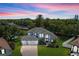 Stunning two-story home featuring a three-car garage, lush landscaping, and a beautiful dusk sky at 13044 Lakeshore Grove Dr, Winter Garden, FL 34787
