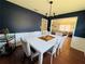 Elegant dining room showcasing a white table with upholstered chairs, modern chandelier, and stylish navy blue walls at 1419 Avenue D Ne, Winter Haven, FL 33881