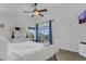 Bright main bedroom with a ceiling fan, wood-look floors, an ensuite bathroom, and sliding glass doors to the patio at 147 Bridgewater Dr, Davenport, FL 33897