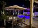 Inviting backyard pool at night, featuring outdoor dining area, lush landscaping, and illuminated palm trees at 14963 Yorkshire Run Dr, Orlando, FL 32828