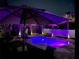 Backyard view of a swimming pool at night, illuminated with colorful lights, surrounded by palm trees and a white fence at 14963 Yorkshire Run Dr, Orlando, FL 32828