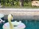 Close up of the gorgeous pool with flamingo floaty, tile waterfall, and lush landscaping at 14963 Yorkshire Run Dr, Orlando, FL 32828