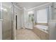 Bright bathroom with a glass-enclosed shower, soaking tub, and neutral-toned tile flooring at 1557 Alligator St, St Cloud, FL 34771
