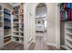 Walk-in closet with custom shelving and wood-look floors, leading to the main bedroom at 1557 Alligator St, St Cloud, FL 34771