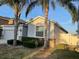 Close-up view of the exterior with stone accents, lush landscaping, and mature palm trees at 1574 Thetford Cir, Orlando, FL 32824