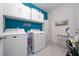 Well-organized laundry room with modern washer, dryer, overhead cabinets, and stylish blue accent wall at 1821 Cayman Cove St., St Cloud, FL 34772