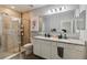 Bathroom featuring a dual sink vanity, a large frameless mirror, and a glass enclosed shower at 2281 Canyon Breeze Ave, Kissimmee, FL 34746