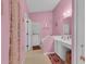 Pink bathroom with white vanity, mirror, and adjacent doorway with decorative curtain at 2398 Queenswood Cir, Kissimmee, FL 34743