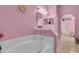 Relaxing bathroom featuring a soaking tub, vanity with mirror, and arched doorway leading to the bedroom at 2398 Queenswood Cir, Kissimmee, FL 34743