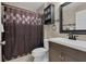 Bathroom with a dark vanity, patterned shower curtain, and tiled walls at 2398 Queenswood Cir, Kissimmee, FL 34743