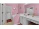 Pink bathroom features white vanity, large mirror, and bathtub with tiled walls at 2398 Queenswood Cir, Kissimmee, FL 34743