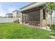 Backyard with grass, white fence, small trees, string lights and a screened-in porch with a wooden picnic table at 3084 Slough Creek Dr, Kissimmee, FL 34744