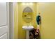 Bright yellow powder room with a pedestal sink, decorative mirror, and cozy lighting at 3084 Slough Creek Dr, Kissimmee, FL 34744