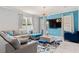 Cozy living room features a gray sectional, blue accents, large windows, and a stylish light fixture at 3084 Slough Creek Dr, Kissimmee, FL 34744