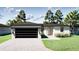 A single-story house with a two-car garage, a concrete driveway, and green grass, situated in a sunny locale at 318 Cocoa Ct, Kissimmee, FL 34758